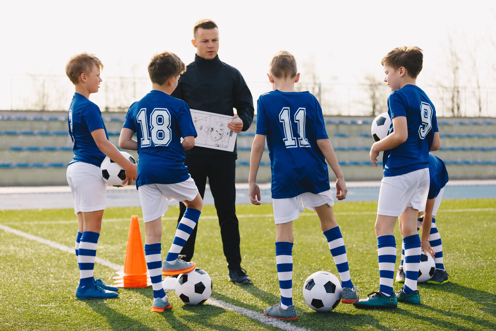 Football Coach Coaching Children. Young Coach Teaching Kids on F